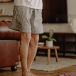 Man practicing balance exercise at home with a focus on legs and barefoot posture.